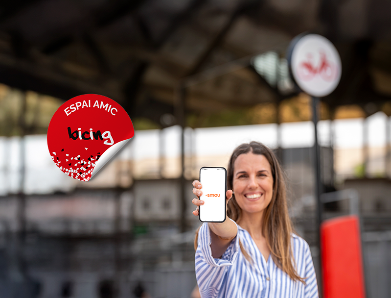 Noia obrint app SMOU al davant d'una estació Bicing