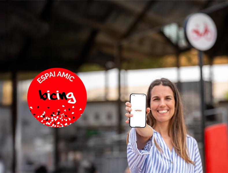 Noia obrint app SMOU al davant d'una estació Bicing
